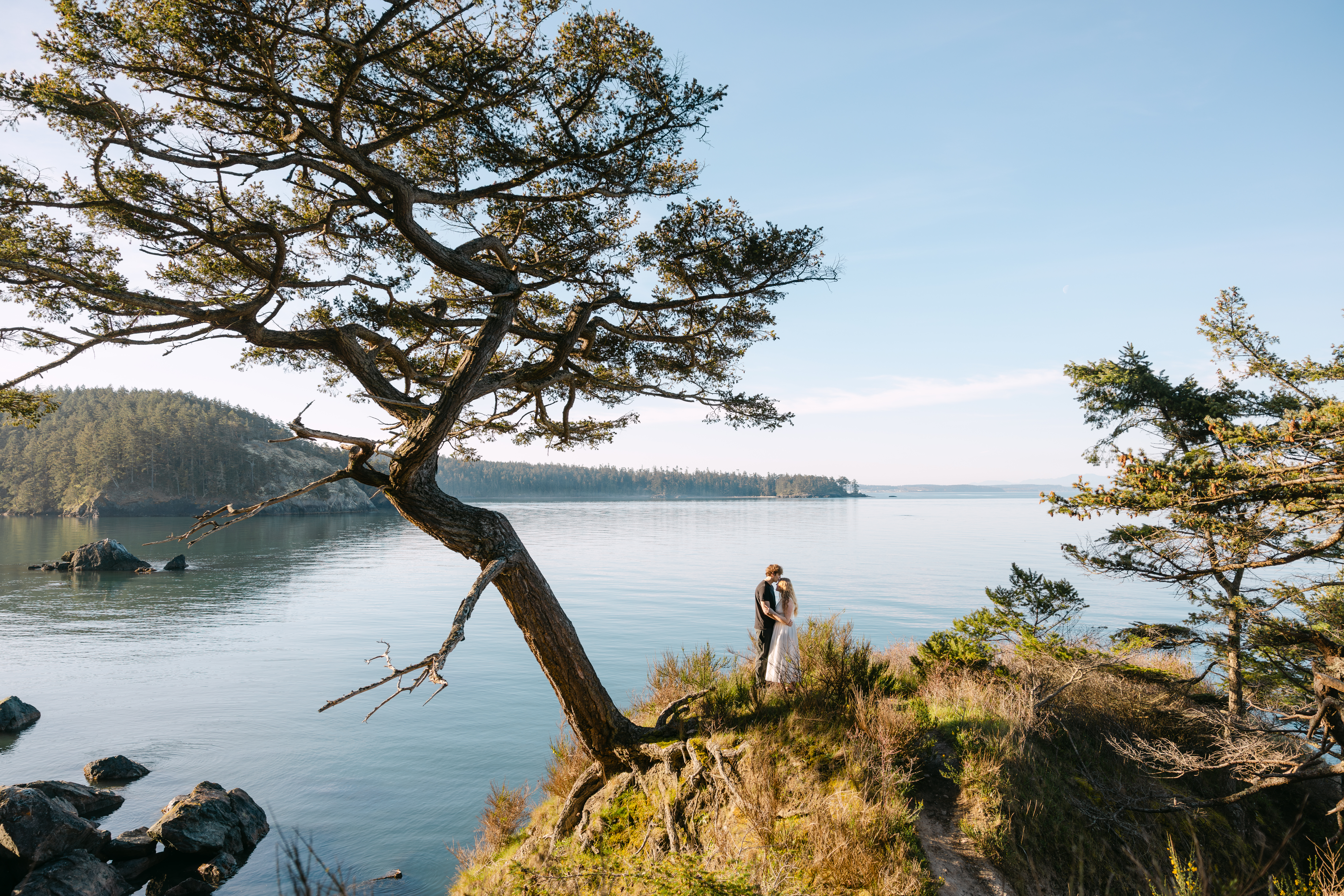 Couple walking by the bluffs along Deception Pass State Park, pausing for a kiss.