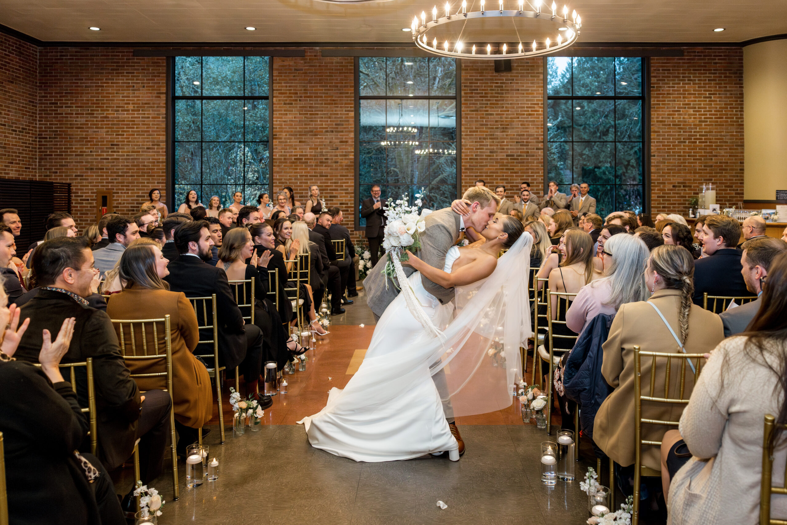 Fall wedding at the Hall at Fauntleroy in West Seattle, couple doing a dip and kissing in the aisle of their ceremony.