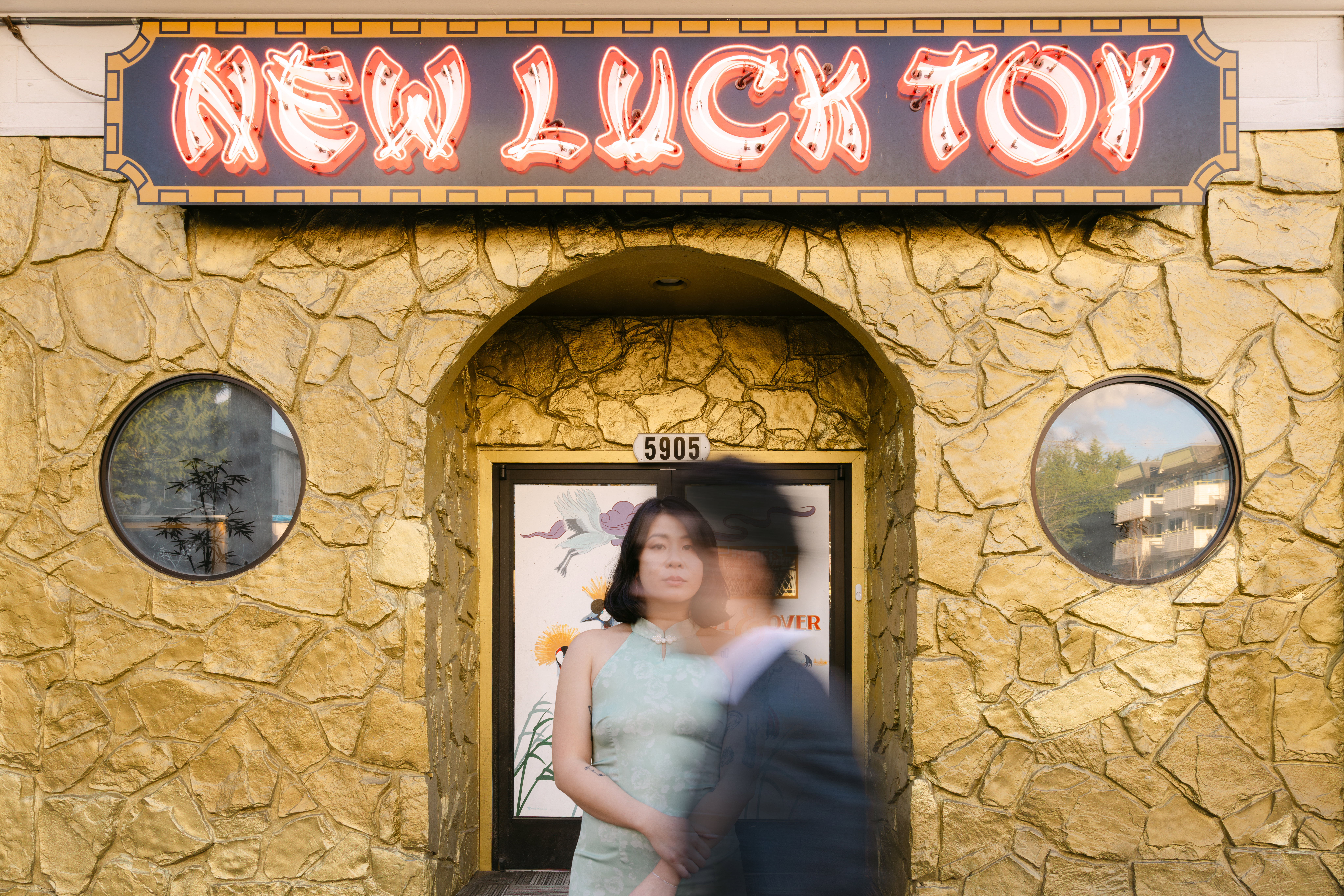 Motion blur of couple walking by each other in front of bar New Luck Toy in West Seattle